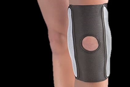 Leg in a grey knee support, on a black background.