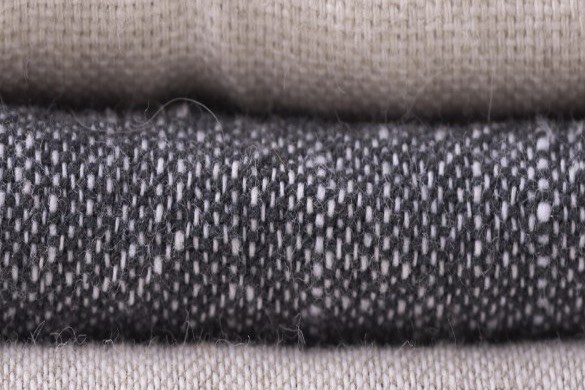 Folded fabric stack with a charcoal tweed band.